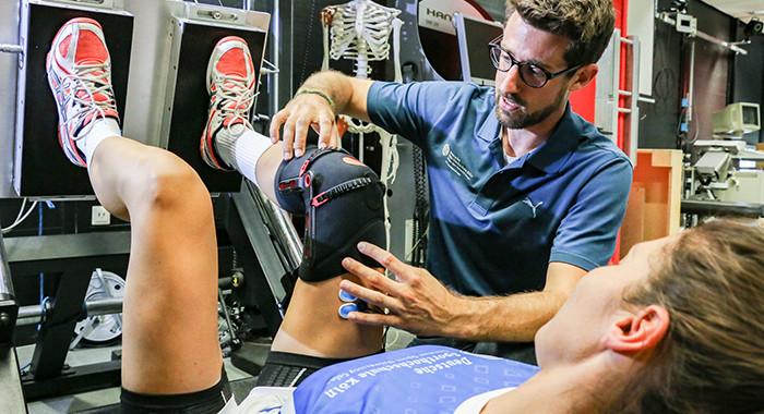 Ein Sportphysiotherapeut behandelt eine Sportlerin.