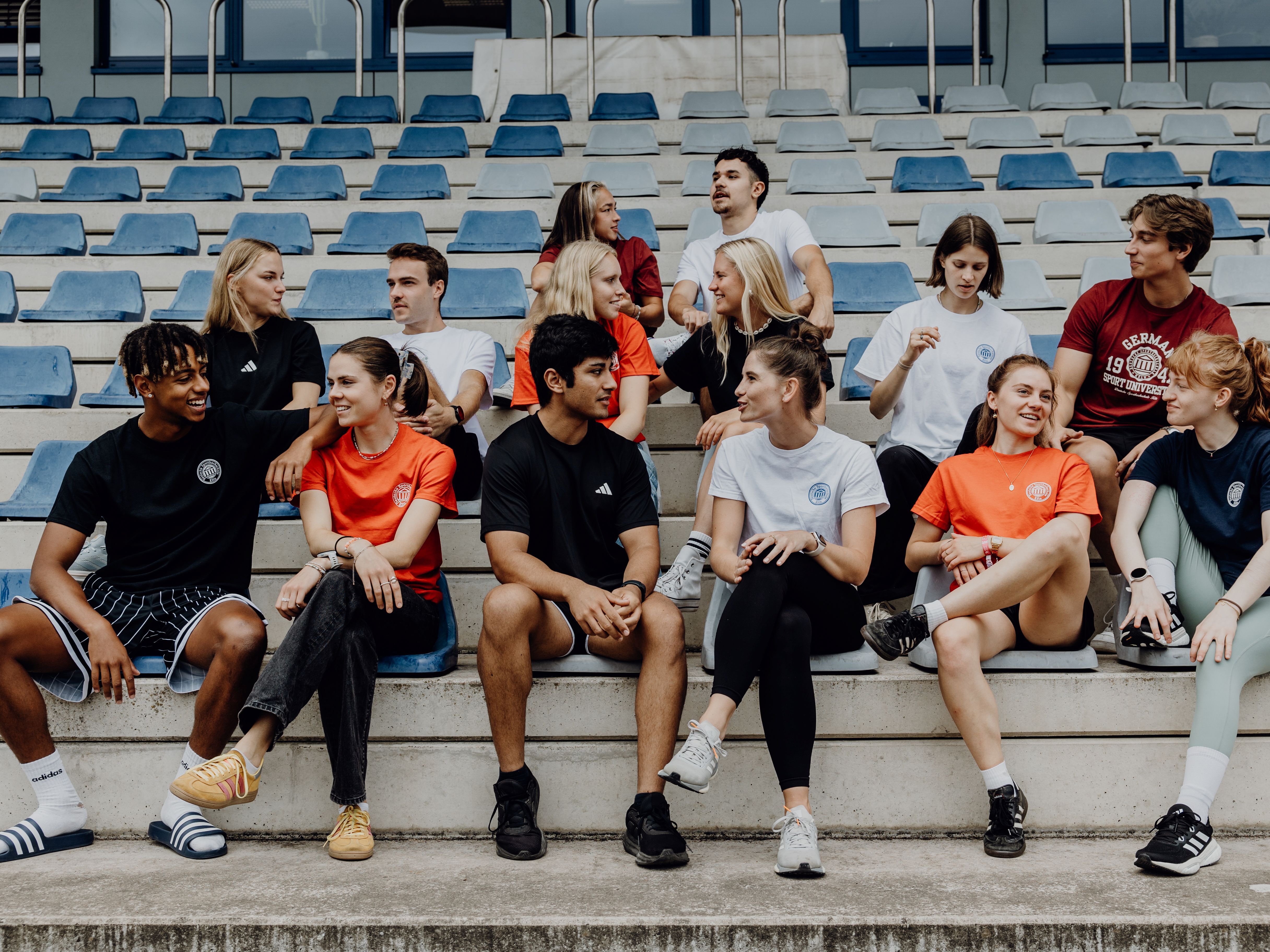 Studierende unterhalten sich auf den Publikumsrängen der Leichtathletikanlage der Deutschen Sporthochschule Köln.
