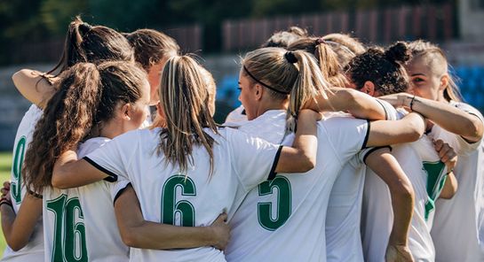 Frauen-Fußballmannschaft bildet einen Kreis.
