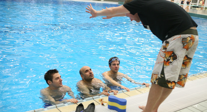 Trainer am Beckenrand mit Schwimmern