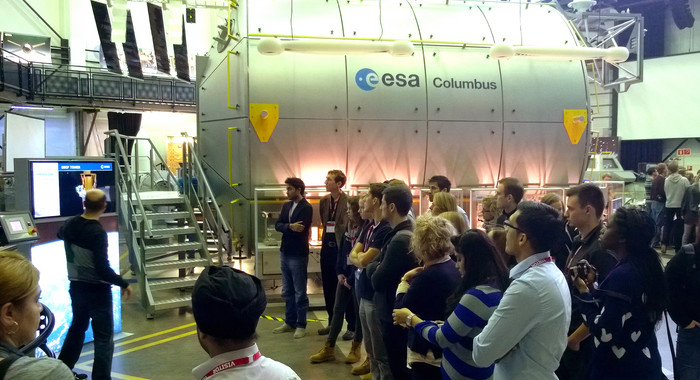 Studierende stehen im Kreis und schauen sich ein Trainingsgerät für Astronauten an.