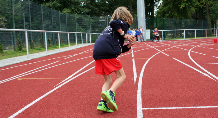 Inwieweit hat Sport einen positiven Einfluss auf die Schlafqualität und die schulische Leistungsfähigkeit bei AD(H)S-Kindern? Ein Kind läuft in einem Leichtathletikstadion