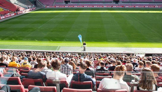 Studierende auf der Tribüne im Fußballstadion
