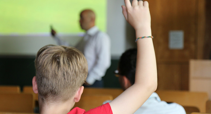 Junge im Hörsaal zeigt auf