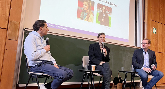 Laura Wontorra sitzt im Hörsaal und hält ein Mikro in der Hand