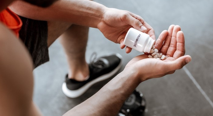 Junger Mann sitzt und schüttet sich Tabletten in die Hand