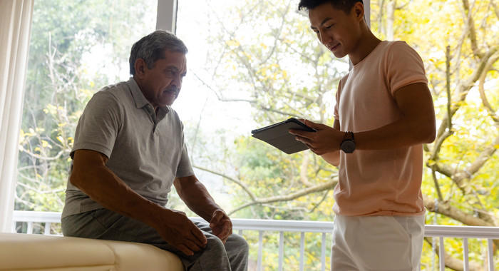 Physiotherapeut untersucht eine Person und verwendet dafür ein Tablet. 