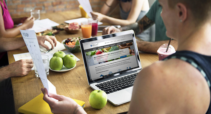 Sportliche Frau lernt ant einem Tisch mit gesunder Ernährung