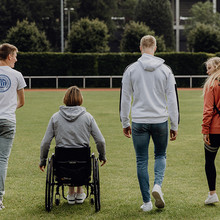 Studierende auf dem Campus, eine Person im Rollstuhl