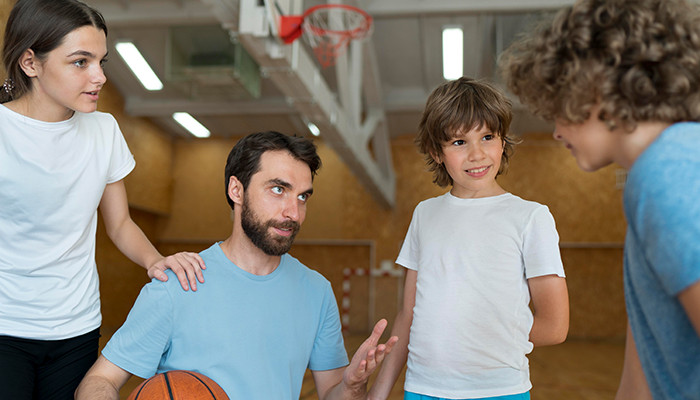 Lehrer redet mit Schülern in der Sporthalle.