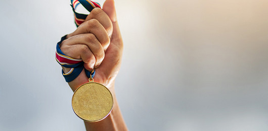 Hand hält Medaille an einem Band hoch