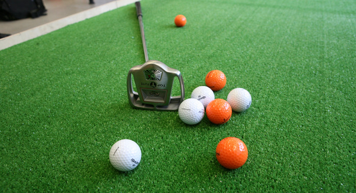 Golfbälle und Schläger auf grünem Grund