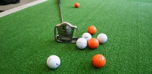 Golfbälle und Schläger auf grünem Grund