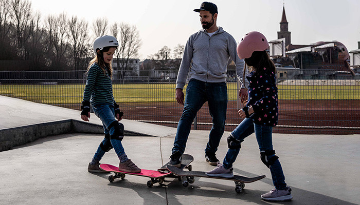 Lehrer erklärt Kindern die Grundtechniken beim Skateboarding.