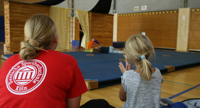 Betreuerin und Kind von hinten in einer Turnhalle