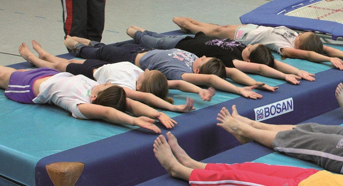 Kinder liegen auf einer Sportmatte