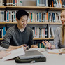 Junge Leute an einem Tisch vor einem Bücherregal