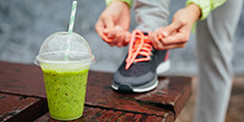 Sportlerin mit einem Smoothie vor sich. Foto: ©Dirima/Shutterstock.com