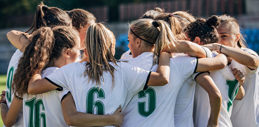 Frauen-Fußballmannschaft bildet einen Kreis.
