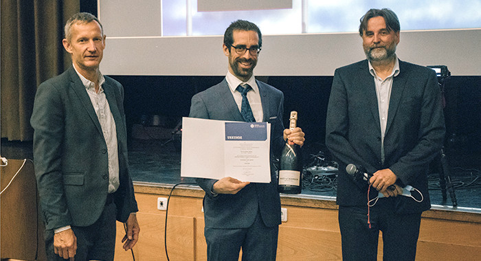 Sylvain Laborde mit Urkunde und Sektflasche und Institutskollegen