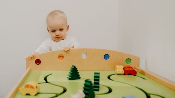 Kleinkind steht vor einem Spieltisch
