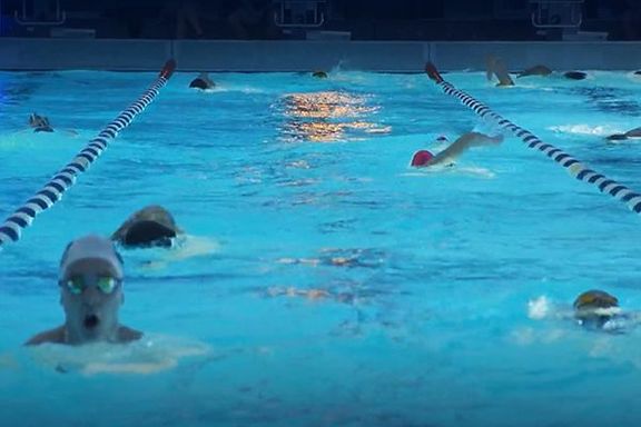 Swimmers in a lit swimming pool
