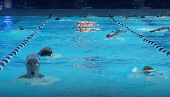 Schwimmer in einem beleuchteten Schwimmbecken
