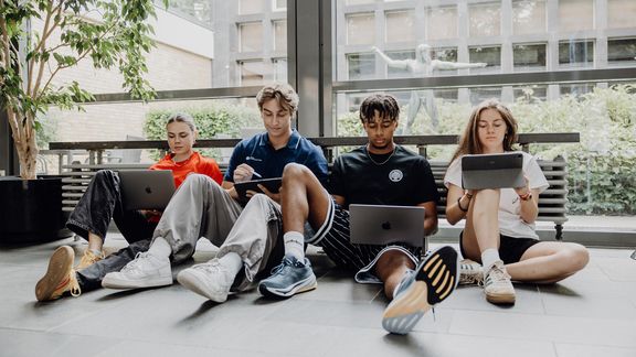 Studierende arbeiten mit Laptops im Foyer der Deutschen Sporthochschule
