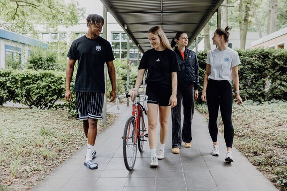 Studierende gehen nebeneinander einen Weg entlang
