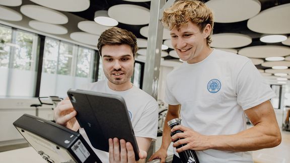 Mann erklärt anderem Mann Ergebnisse auf dem Tablet, Fitness Trainer Lizenz

