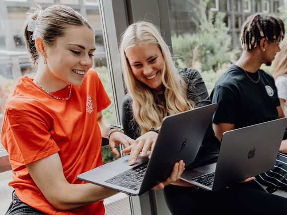 Drei Studierende arbeiten mit Laptops im Foyer der Deutschen Sporthochschule
