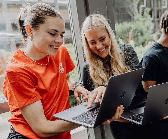 Drei Studierende arbeiten mit Laptops im Foyer der Deutschen Sporthochschule
