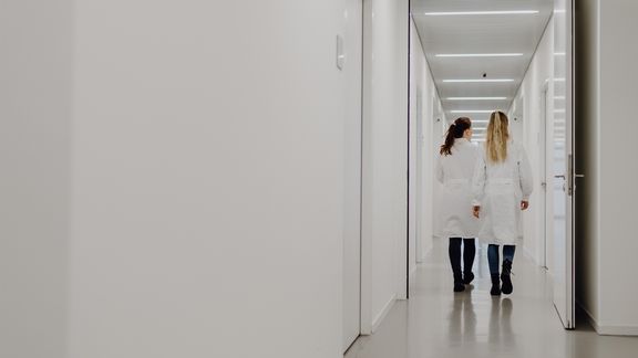 Foto von zwei Person die in weißem Kittel durch Gang gehen
