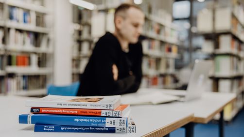 Student lernt mit Laptop in der Bibliothek der Deutschen Sporthochschule
