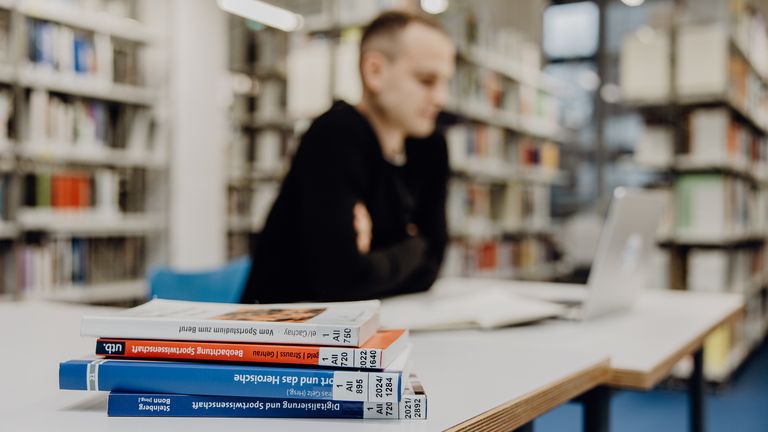 Student lernt mit Laptop in der Bibliothek der Deutschen Sporthochschule
