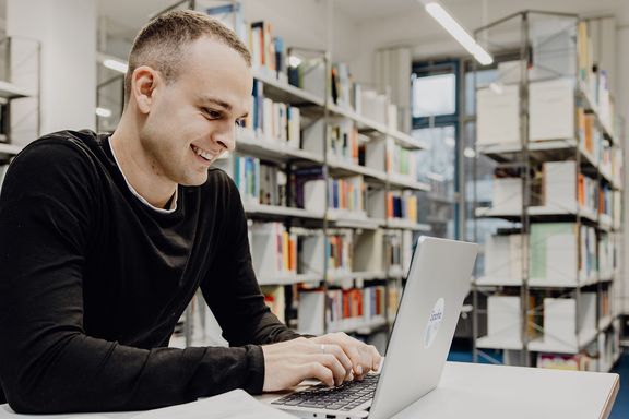 Student lernt mit Laptop in der Bibliothek der Deutschen Sporthochschule
