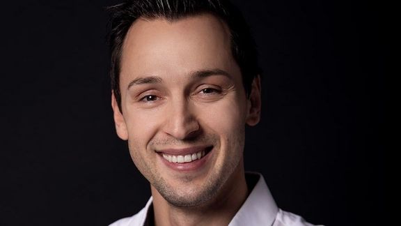 Portrait eines jungen Mannes mit dunkle, kurzen Haaren und einem hellen Oberhemd
