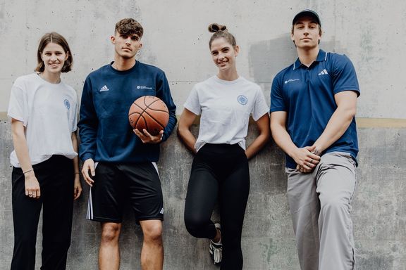 Studierende der Deutschen Sporthochschule Köln stehen gemeinsam an einer Wand, eine Person mit Basketball.
