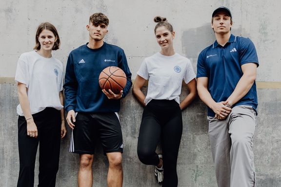 Studierende der Deutschen Sporthochschule Köln stehen gemeinsam an einer Wand, eine Person mit Basketball.
