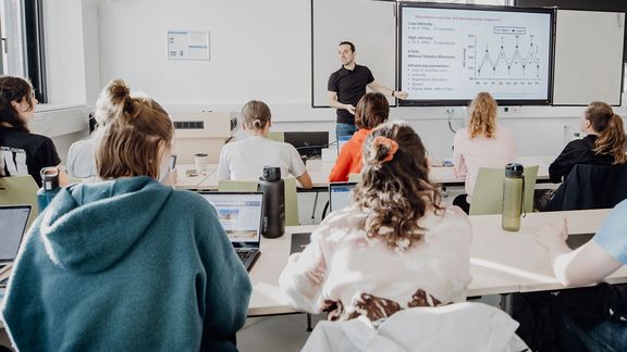Dozent unterrichtet Studierende im Seminarraum
