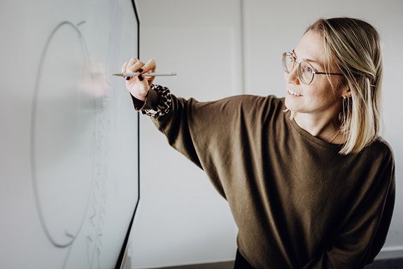 Frau beschriftet leuchtendes Whiteboard mit einem Stift
