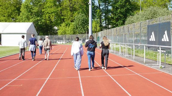 Personen laufen über die Tartanbahn der Spoho und sprechen miteinander 
