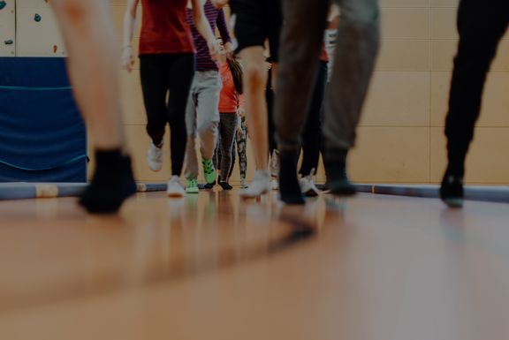 Nahaufnahme von den Beinen einiger laufender Kinder in einer Turnhalle
