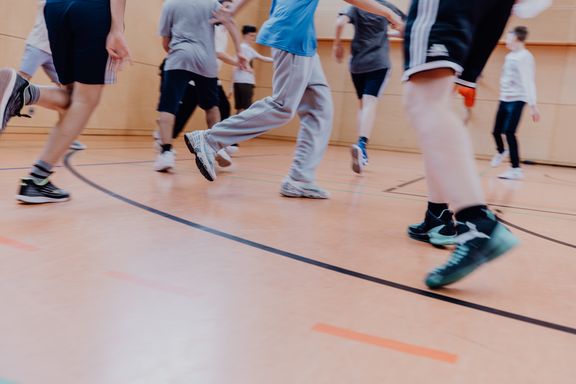 Unterkörper von vielen Kinder, die durch einen Turnhalle laufen
