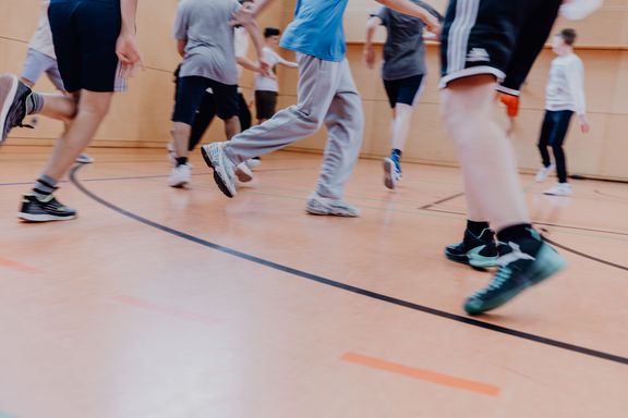 Unterkörper von vielen Kinder, die durch einen Turnhalle laufen
