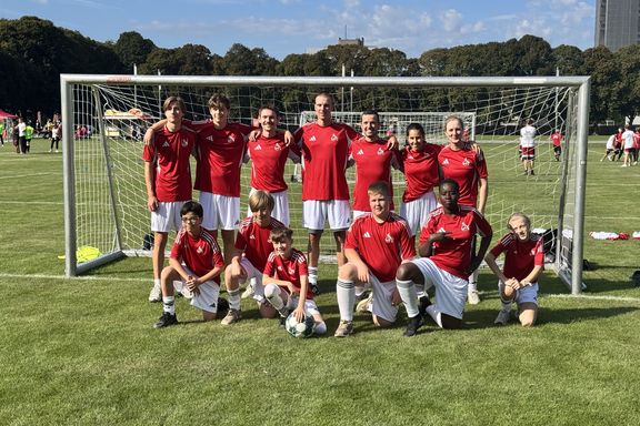 Team in roten Trikots vor einem Fußballtor auf einer Wiese

