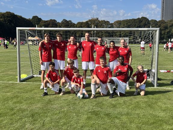 Team in roten Trikots vor einem Fußballtor auf einer Wiese
