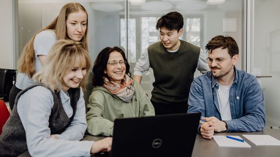 Personen betrachten lächelnd Inhalt auf einem Laptop

