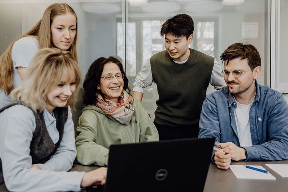 Personen betrachten lächelnd Inhalt auf einem Laptop
