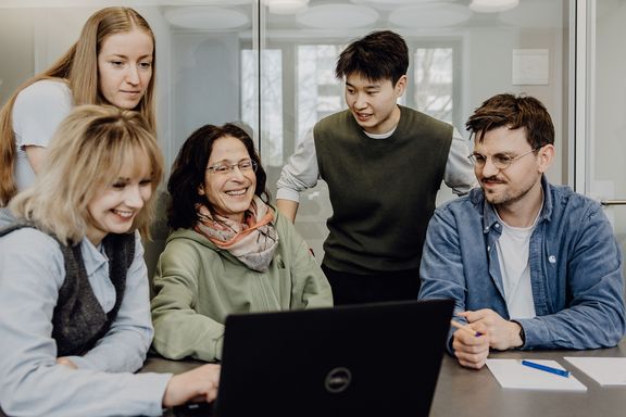 Personen betrachten lächelnd Inhalt auf einem Laptop

